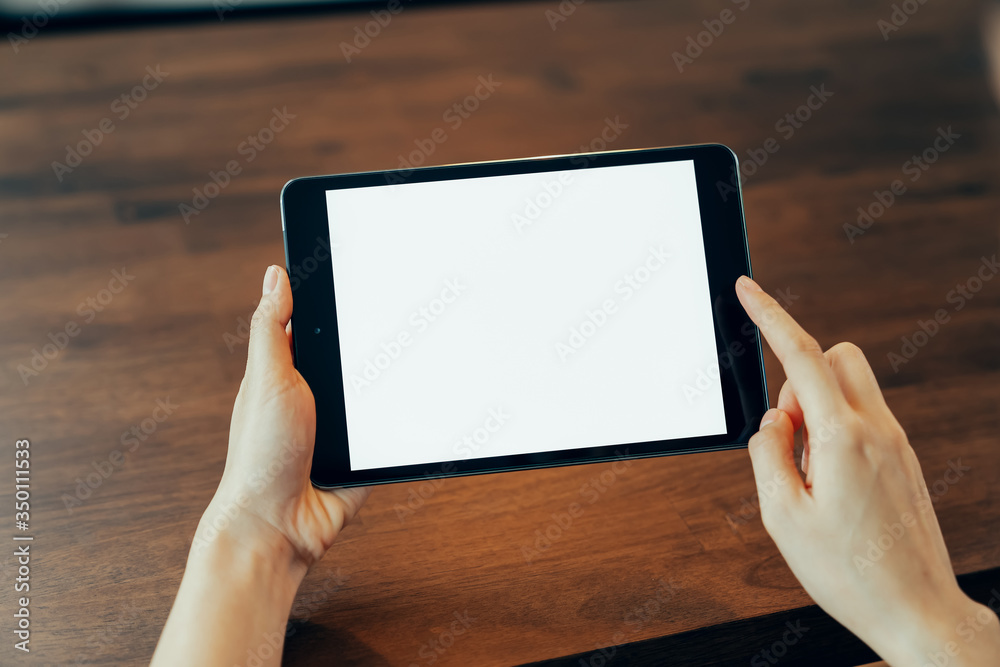 Closeup of woman hand holding digital tablet on the table and the screen is blank.