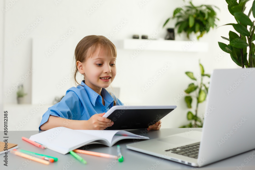 Remote lessons. The child smiles happily and gets knowledge remotely. Little girl study online learning from home. Online school. Remote lessons. The child smiles happily and gets knowledge remotely. Little girl study online learning from home. Online school.