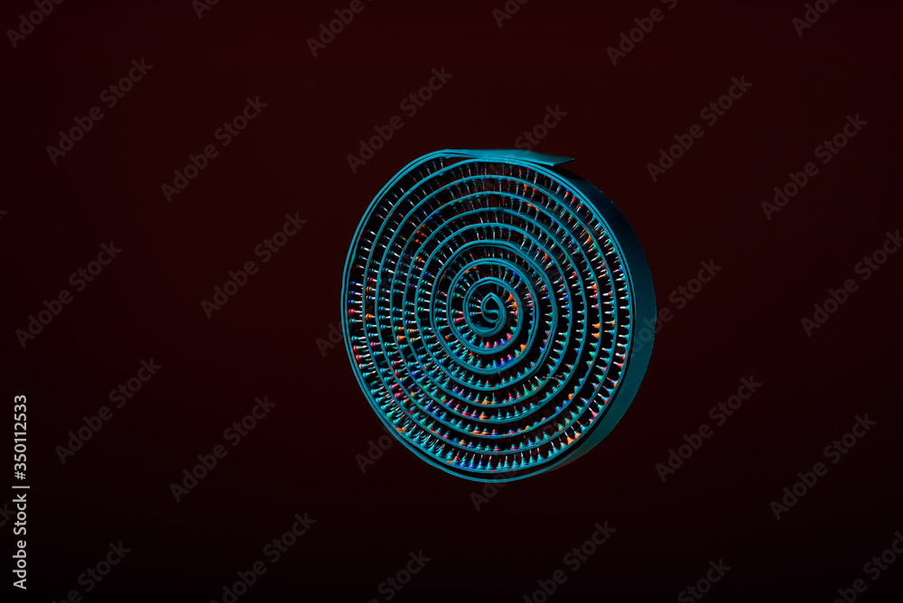 Green massage tape from rubber and metal needles twisted into a circle, on a dark background hangs in the air. Advertising, thematic and subject shooting. For relaxation and health.