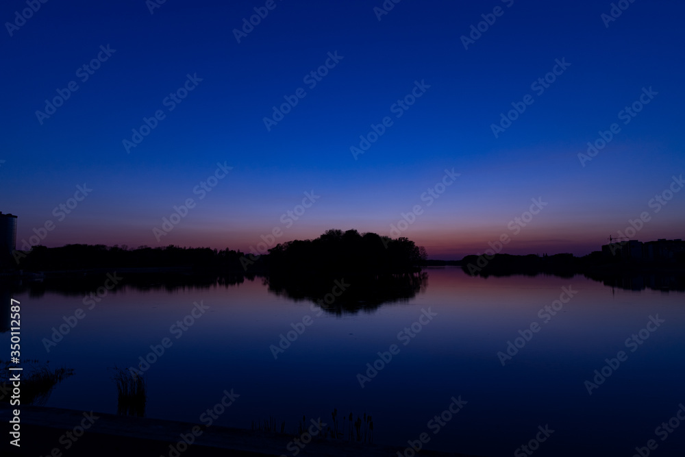 Obraz premium island on lake landscape silhouette idyllic long exposure landscape scenic view in purple dark blue colorful of twilight lighting after sunset