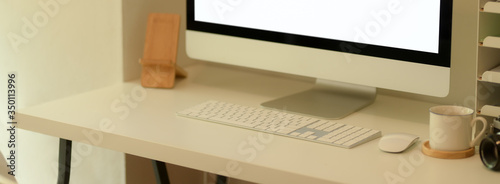 Cropped shot of simple office desk with blank screen computer and office supplies