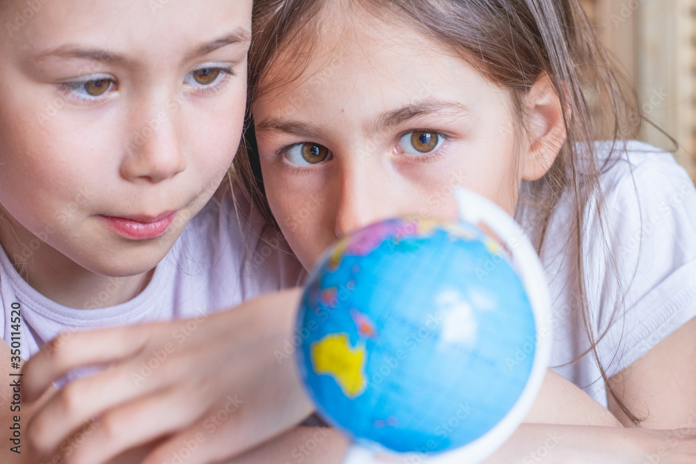Child girl are sitting at home and looking at the globe, dreaming about traveling around the world. Child girl are sitting at home and looking at the globe, dreaming about traveling around the world.