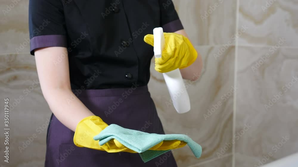 Modern cleaning service concept. Close-up view on female housekeeper holding cleaning wiper or duster in hands with yellow gloves, spray cleaner, wet rag. Clean hotel room. 4 k footage Modern cleaning service concept. Close-up view on female housekeeper holding cleaning wiper or duster in hands with yellow gloves, spray cleaner, wet rag. Clean hotel room. 4 k footage