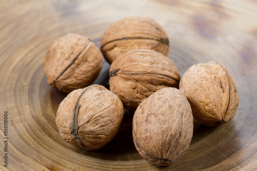 Walnuts close-up on a table from a cut of a poplar trunk, growth rings. Burnt wood texture. Walnuts close-up on a table from a cut of a poplar trunk, growth rings. Burnt wood texture.