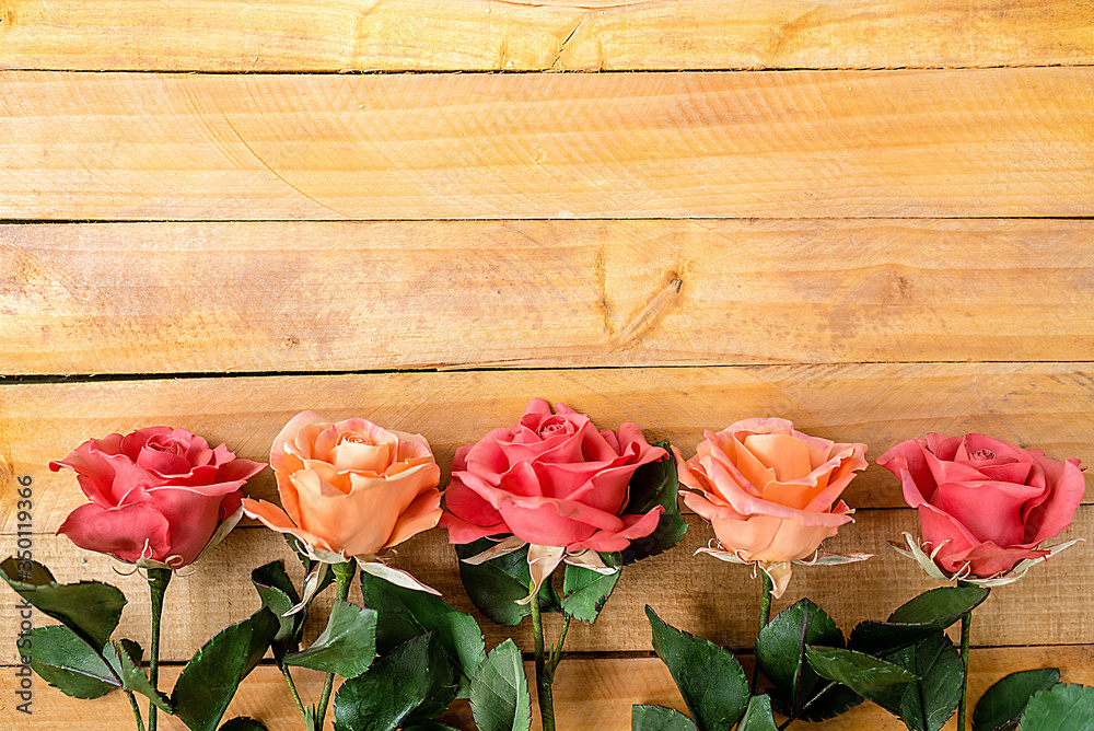 Handmade roses lie on a wooden background. Background layout with free text space.