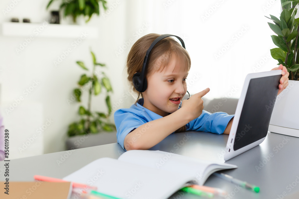 Remote lessons. The child smiles happily and gets knowledge remotely. Little girl study online learning from home. Online school. Remote lessons. The child smiles happily and gets knowledge remotely. Little girl study online learning from home. Online school.