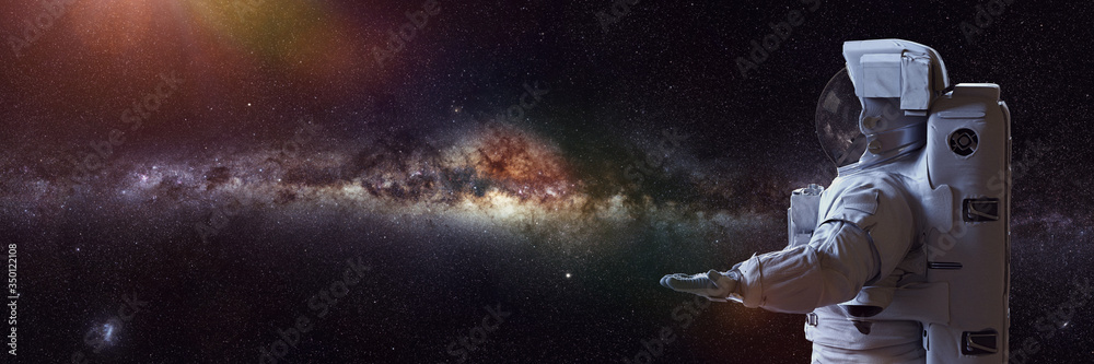 astronaut presenting an empty space in front of the Milky Way galaxy 