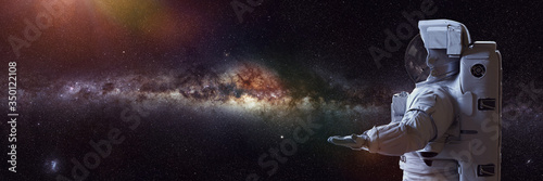 astronaut presenting an empty space in front of the Milky Way galaxy  © dottedyeti