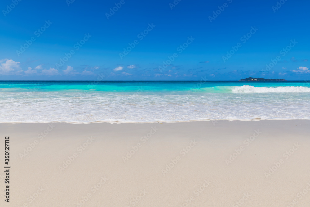 Beautiful ocean wave on clean sandy beach. Summer background, beach with turquoise tropical sea water.