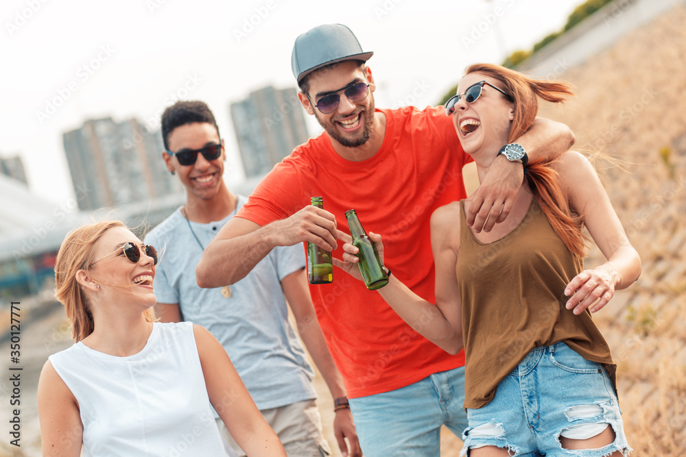 Group of cheerful friends walking through the city by the river talking and having fun. Group of cheerful friends walking through the city by the river talking and having fun.