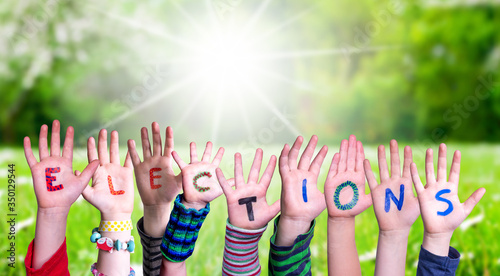 Children Hands Building Colorful Word Elections. Green Grass Meadow As Background