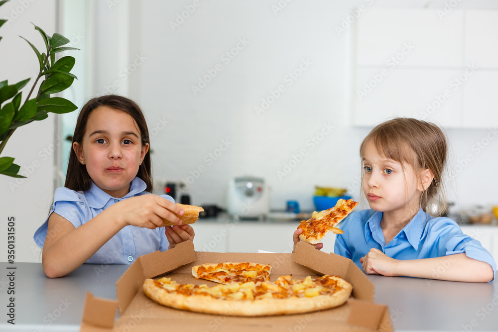 Two happy little child girl friends eating pizza slices. Two happy little child girl friends eating pizza slices.