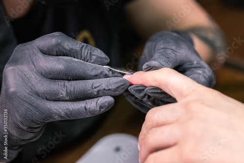 Woman use electric nail file drill in beauty salon. Nails manicure process in detail. Gel polish concept. photo