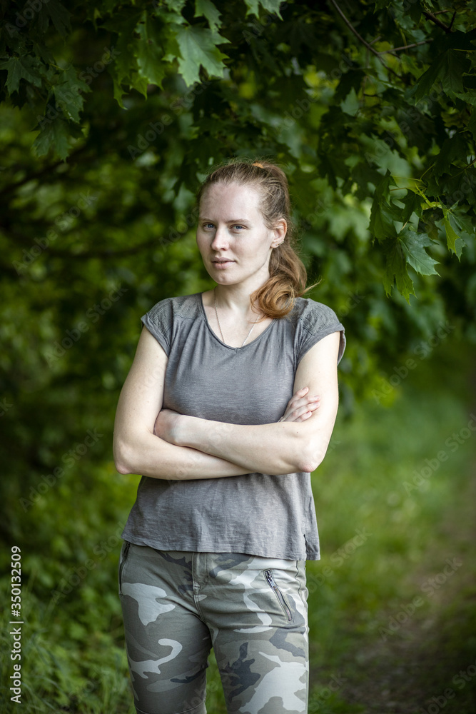 Portrait of a beautiful woman with long hair on a green background. The girl is wearing a gray short-sleeved T-shirt and army pants. Portrait of a beautiful woman with long hair on a green background. The girl is wearing a gray short-sleeved T-shirt and army pants.