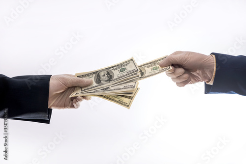 Two hands holding or gives US dollar in medical gloves for protect, quarantine period