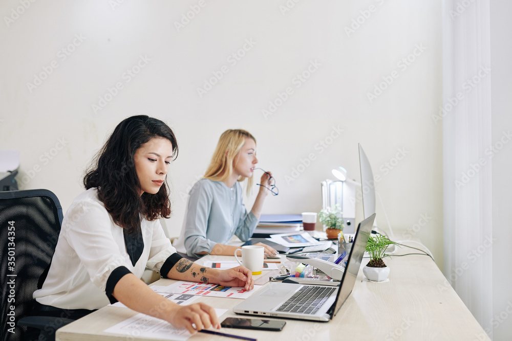 Concentrated UI and UX designers working on project at office desk Concentrated UI and UX designers working on project at office desk