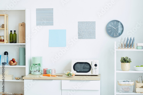 Background image of contemporary kitchen interior in pastel colors with focus on microwave oven and analog clock, copy space photo