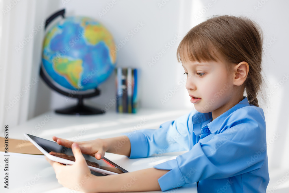 Smart little schoolgirl with digital tablet in a classroom. Child in an elementary school. Education and learning for kids. Smart little schoolgirl with digital tablet in a classroom. Child in an elementary school. Education and learning for kids.