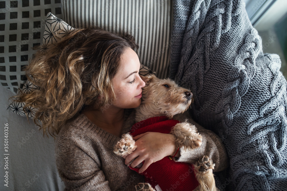 Top view of young woman relaxing indoors on sofa at home with pet dog. Top view of young woman relaxing indoors on sofa at home with pet dog.