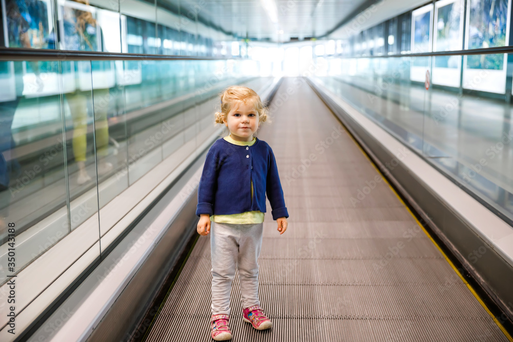 Adorable little toddler girl at the airport. Lovely child walking to the gate and going on family vacations by plane. Positive happy child.