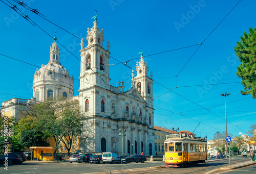 Estrela Basilica or the Royal Basilica is an ancient carmelite convent in Lisbon, Portugal. Vintage yellow tram on the old streets of Lisbon. Famous landmarks of Lisbon.
