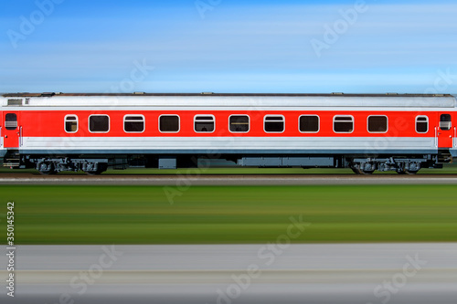 Red train In motion. Side view of the moving train runs on railway in the blurred background