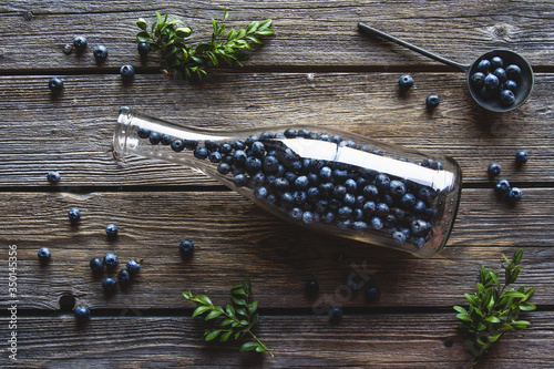 Blueberries in a bottle on wooden background