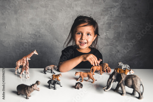 Little girl playing with animal toys in playroom photo