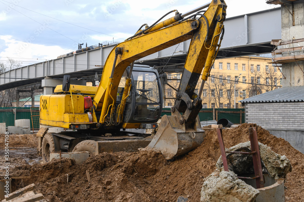 Yellow excavator on wheels digs the ground. Earthwork with an excavator. Yellow excavator on wheels digs the ground. Earthwork with an excavator.