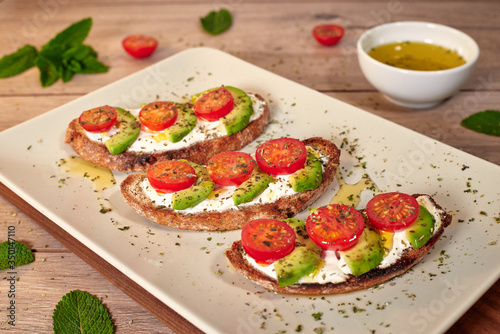 Healthy food, tomato and avocado toasts on a wooden cutting table.