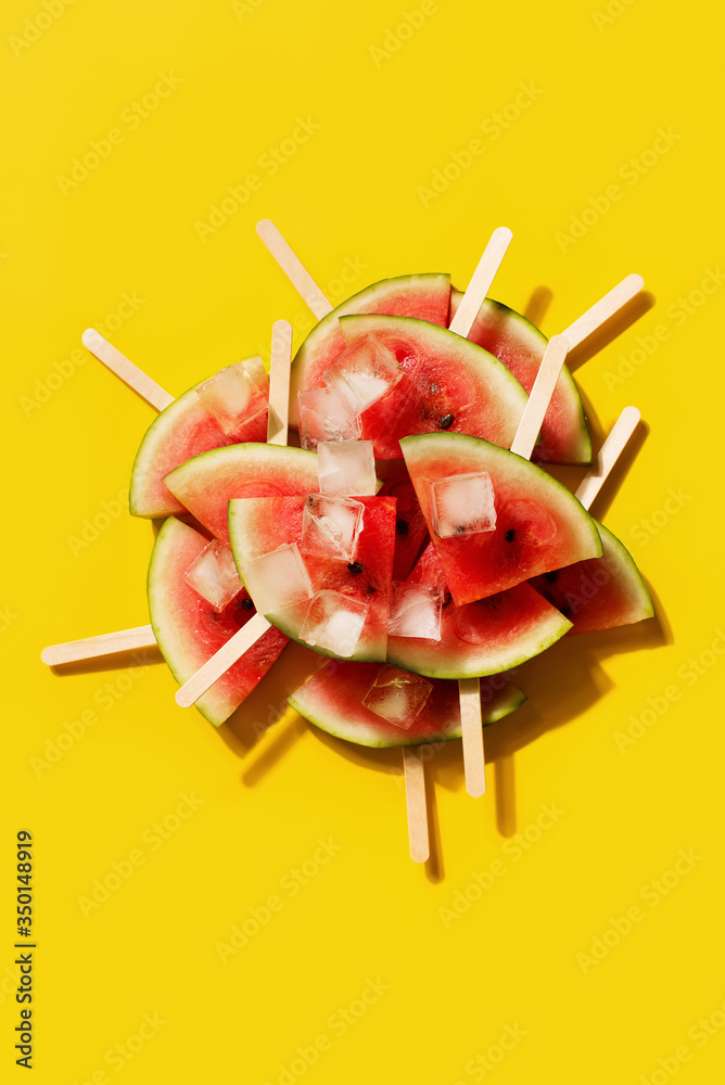 Watermelon group or stack of slices with ice flat lay on yellow background Watermelon group or stack of slices with ice flat lay on yellow background