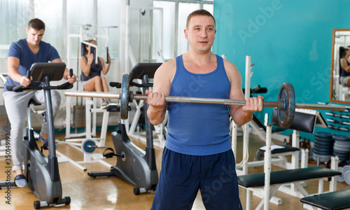 Man practicing with barbell in sport club