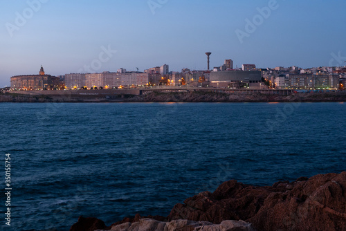 Barrio de Monte Alto con la Torre de Hércules de la ciudad de A Coruña al anochecer, fotografiados desde la ensenada del Orzán.