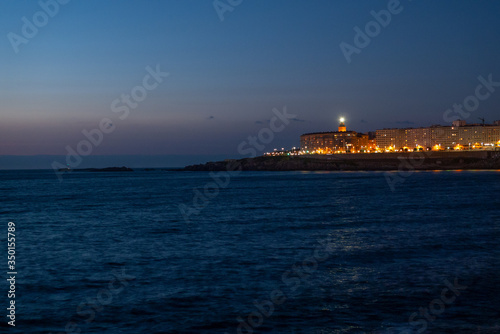 Barrio de Monte Alto y Torre de Hércules de la ciudad de A Coruña al anochecer, fotografiados desde la ensenada del Orzán.