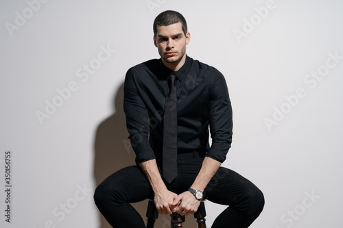 Young handsome businessman in black shirt and black suit. Confident young businessman posing on white background