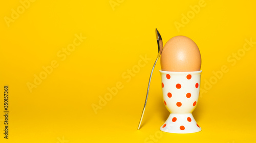 Ei in einem Eierbecher mit Löffel isoliert vor gelbem Hintergrund photo