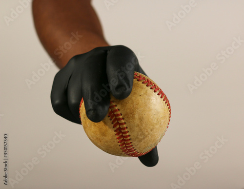 Pitcher grip baseball while wearing a latex / nylon glove to stop the spread of germs. showing curveball grip photo