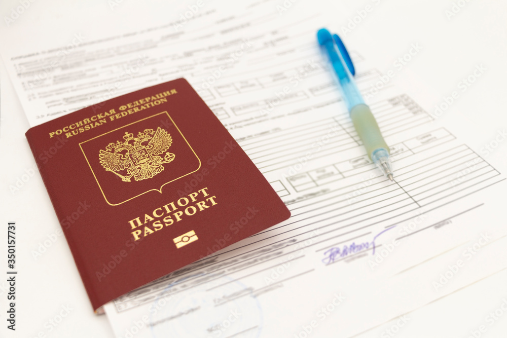 The Russian passport contains documents for filling in data and signatures on a white background. There is a pen on the sheet. The Russian passport contains documents for filling in data and signatures on a white background. There is a pen on the sheet.