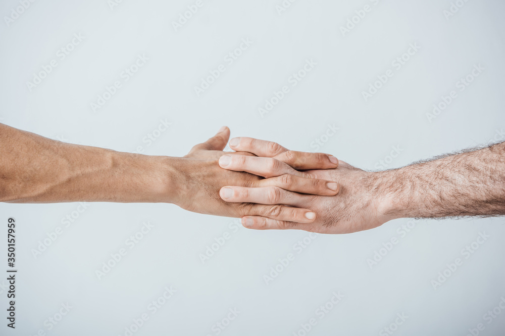Cropped view of men holding hands isolated on grey Cropped view of men holding hands isolated on grey
