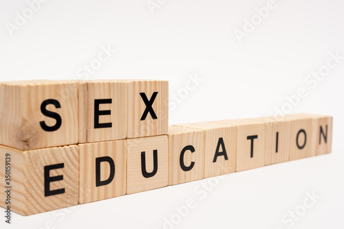 selective focus of wooden cubes with sex education lettering isolated on white