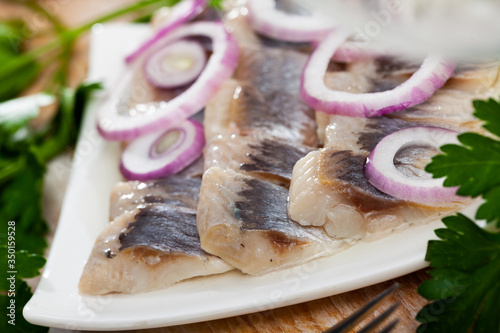 Marinated herring with sliced onion and parsley