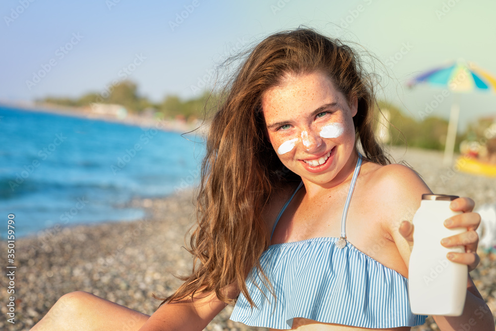 Pretty young  freckled girl with  long blonde hair relaxing on the beach near sea, summer, vacation, travel.