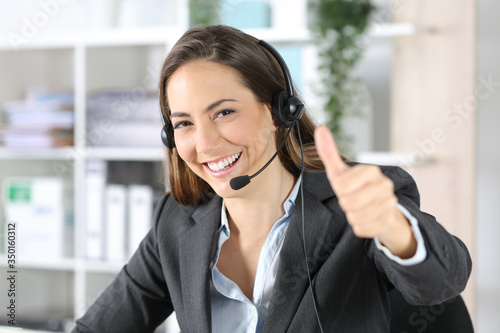 Happy telemarketer with thumbs up looking camera at office
