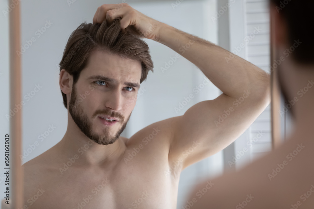 Unhappy young caucasian man look in mirror in bathroom dissatisfied with hair loss or receding hairline, anxious millennial male worried about dandruff on scalp, body hygiene, health problem concept Unhappy young caucasian man look in mirror in bathroom dissatisfied with hair loss or receding hairline, anxious millennial male worried about dandruff on scalp, body hygiene, health problem concept