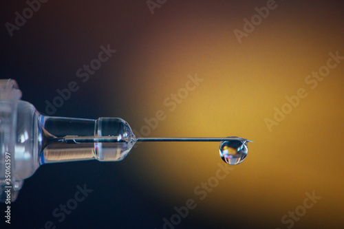 Syringe with drops, detail macro photo. Gold medal in background. Doping and drugs in sport, concept photo. Black background