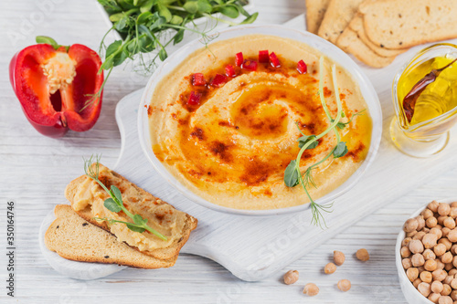 Healthy homemade creamy hummus with olive oil, microgreen and crispbread on white wooden background. Healthy and diet food concept