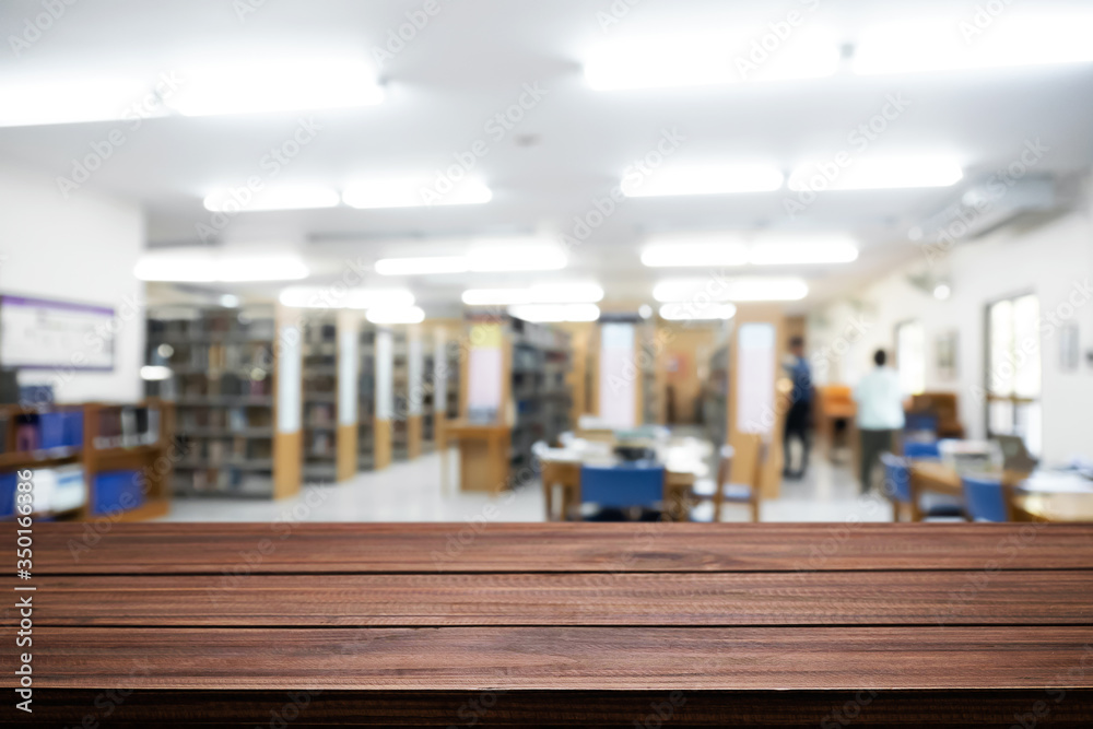 Fototapeta premium Empty wooden desk space platform with library background for product display montage. Education concept.