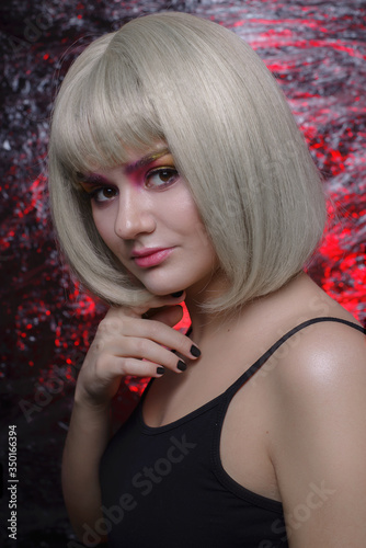 fashion, beautiful girl with bright make-up in a black t-shirt. ready-made image for Halloween. close-up portrait. portrait with pink light on a background with cling film