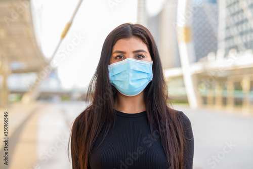 Face of young Indian woman with mask for protection from corona virus outbreak at the skywalk bridge