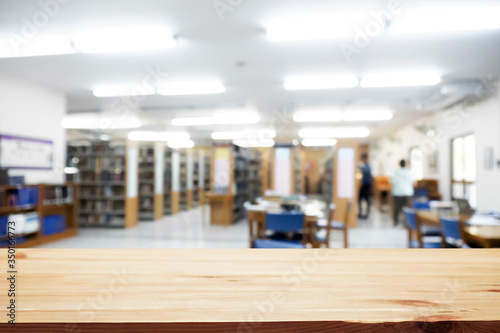 Empty wooden desk space platform with library background for product display montage. Education concept.